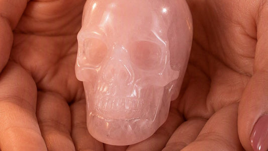 Hand-held rose quartz crystal skull in warm natural light