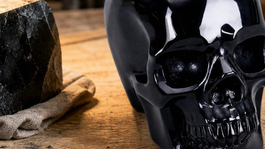 Hand-carved black obsidian crystal skull displayed on a wooden work surface
